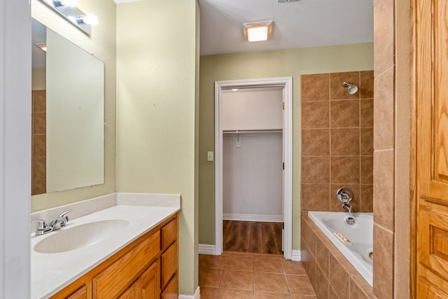 full bath featuring a walk in closet, vanity, baseboards, and tile patterned floors