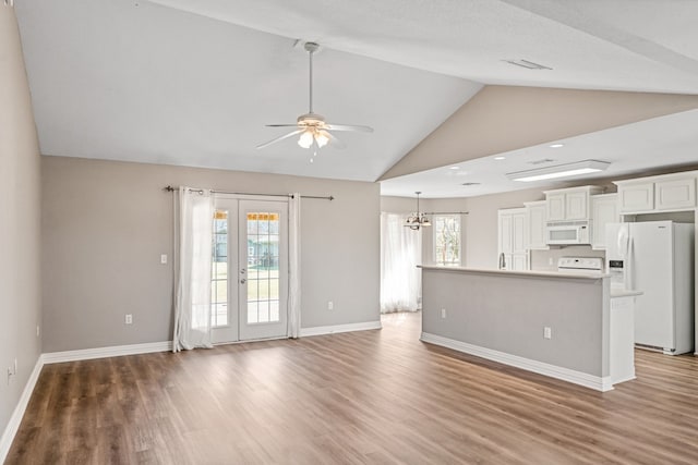 unfurnished living room with vaulted ceiling, french doors, light wood-type flooring, and baseboards