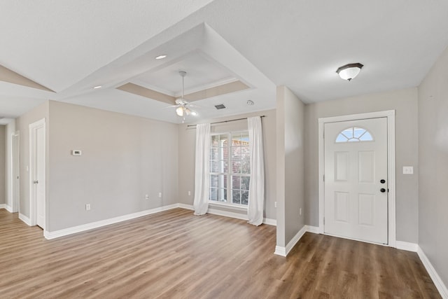 foyer entrance featuring a tray ceiling, visible vents, ceiling fan, wood finished floors, and baseboards