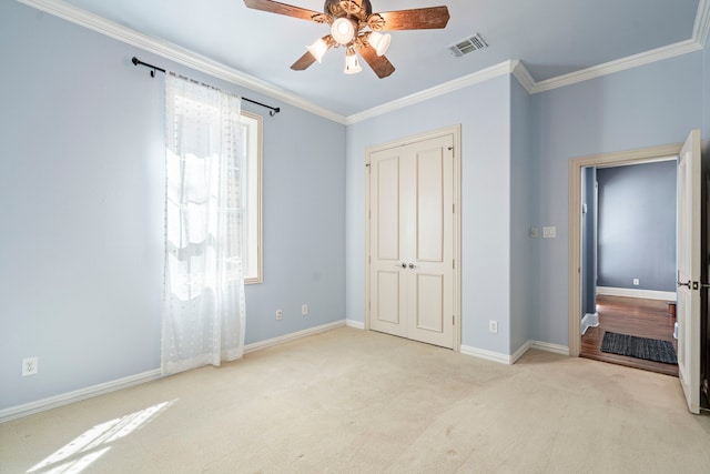 unfurnished bedroom featuring visible vents, baseboards, crown molding, carpet flooring, and a closet