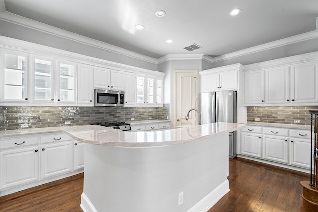 kitchen with white cabinets, range with gas stovetop, stainless steel microwave, dark wood finished floors, and glass insert cabinets