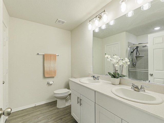 full bathroom featuring visible vents, a shower stall, wood finished floors, and a sink