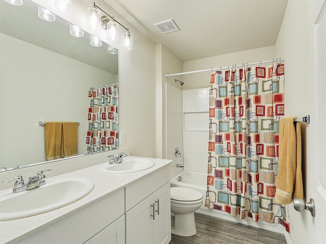 bathroom with a sink, visible vents, toilet, and wood finished floors