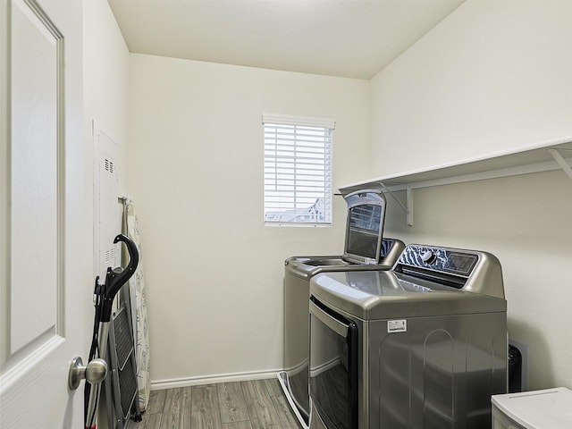 laundry area featuring baseboards, separate washer and dryer, wood finished floors, and laundry area