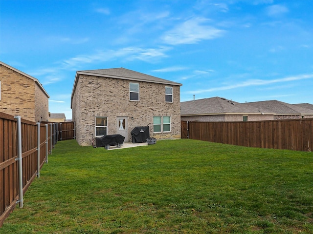 rear view of house featuring a patio area, a lawn, brick siding, and a fenced backyard