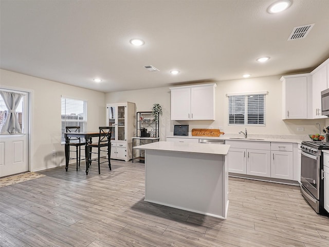 kitchen with a sink, visible vents, light wood finished floors, and stainless steel appliances