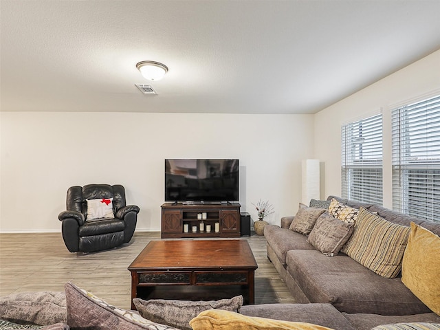 living area with wood finished floors, visible vents, and baseboards