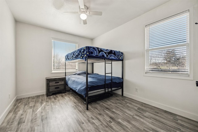 bedroom with multiple windows, baseboards, and wood finished floors