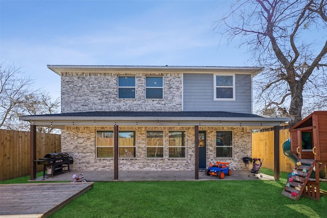 back of house featuring a yard, a fenced backyard, a playground, and brick siding