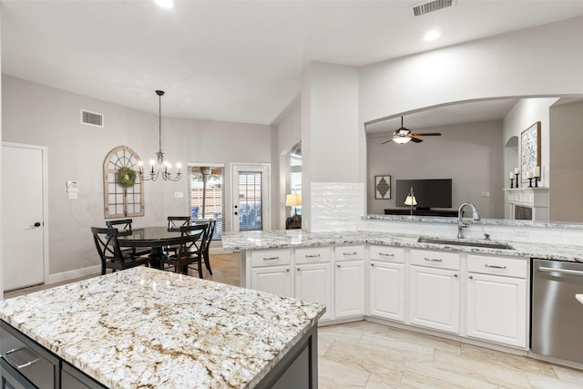 kitchen with light stone counters, stainless steel dishwasher, a sink, and visible vents