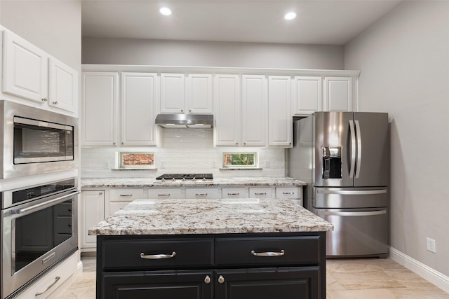 kitchen featuring dark cabinets, under cabinet range hood, stainless steel appliances, white cabinets, and tasteful backsplash