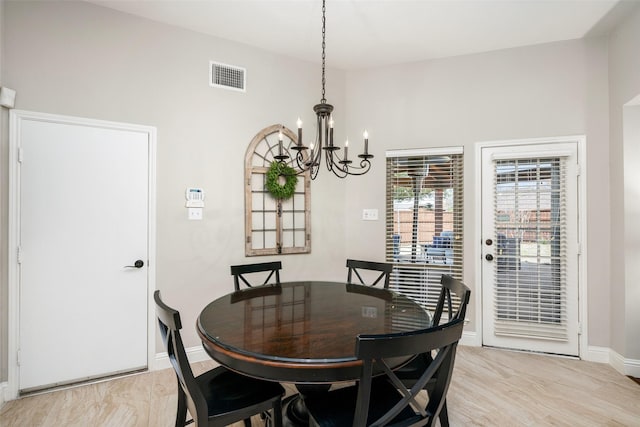 dining space with light wood finished floors, an inviting chandelier, visible vents, and baseboards