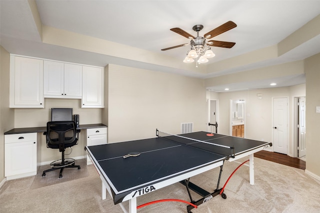 recreation room with built in desk, a raised ceiling, visible vents, a ceiling fan, and baseboards