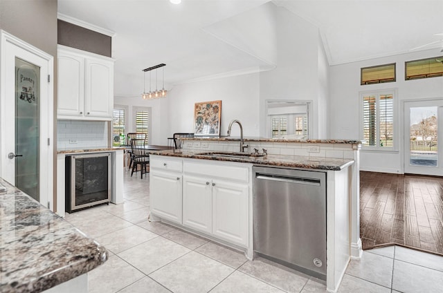 kitchen with backsplash, a sink, dark stone counters, beverage cooler, and dishwasher