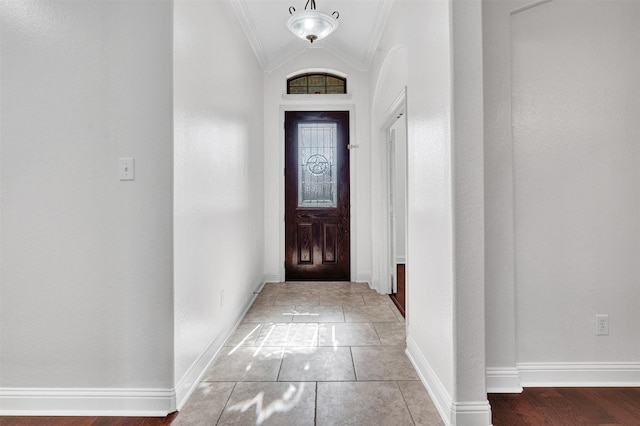 entryway with lofted ceiling, ornamental molding, and baseboards