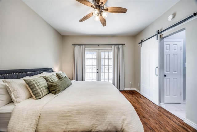 bedroom featuring french doors, a barn door, wood finished floors, and baseboards