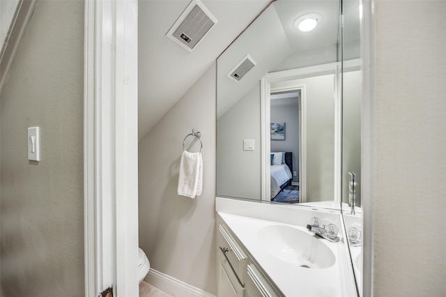 ensuite bathroom with toilet, visible vents, vaulted ceiling, and vanity