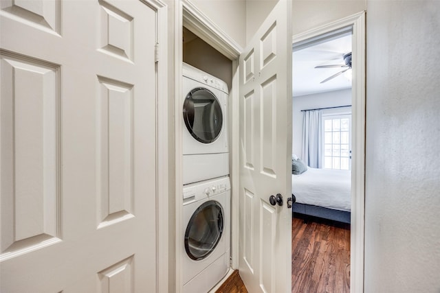 laundry area featuring laundry area, dark wood-type flooring, stacked washing maching and dryer, and a ceiling fan