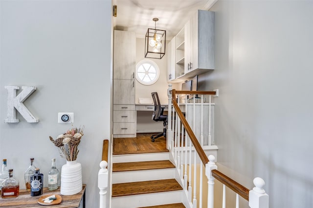 stairs featuring built in desk and wood finished floors