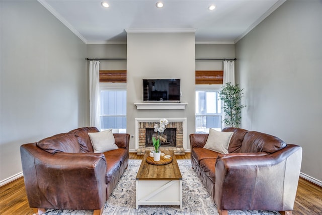 living area featuring baseboards, wood finished floors, crown molding, a brick fireplace, and recessed lighting