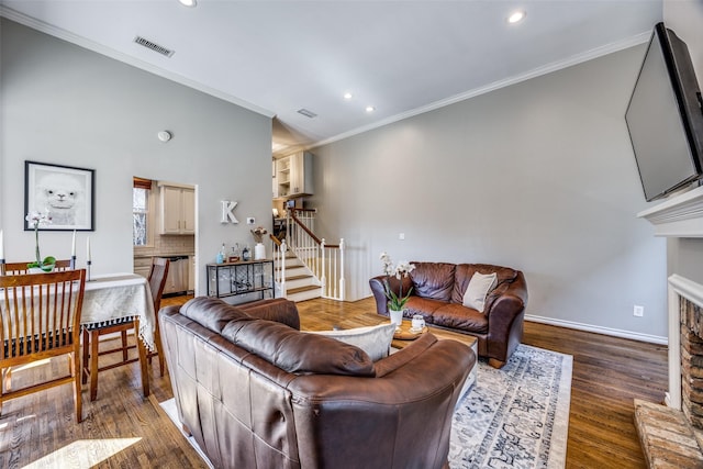 living area with visible vents, a fireplace with raised hearth, stairway, ornamental molding, and wood finished floors