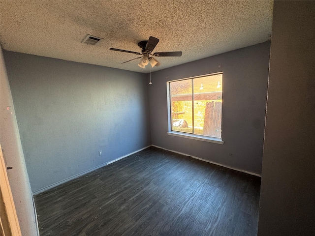 empty room with dark wood-type flooring, visible vents, a textured ceiling, and baseboards