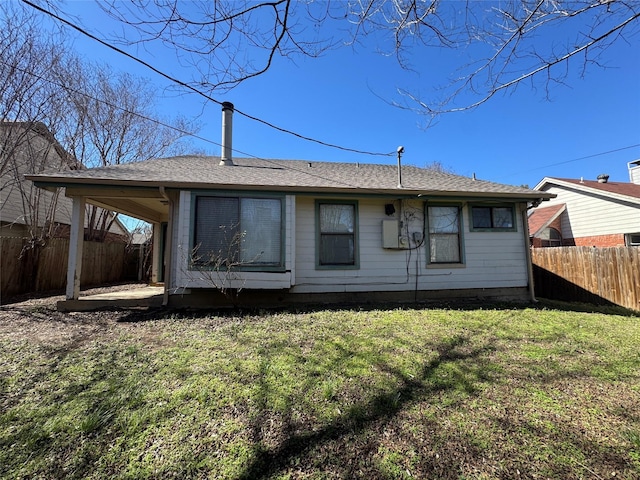 back of house with a fenced backyard and a lawn