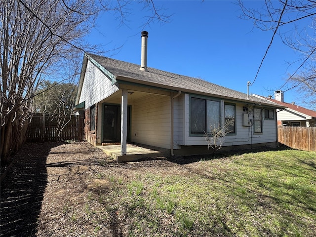 rear view of property featuring a fenced backyard, a yard, and a patio