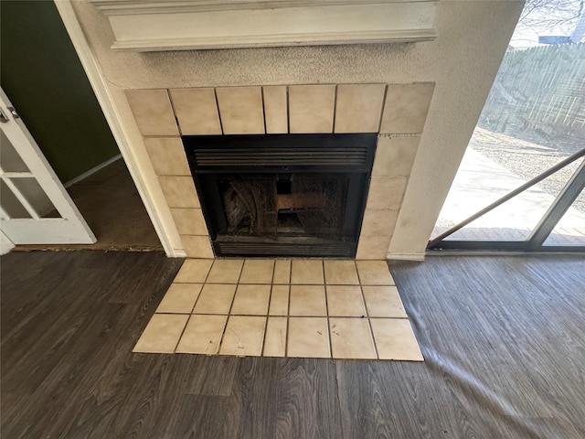 details with wood finished floors, a tile fireplace, and baseboards