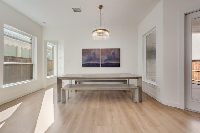 dining space with light wood-style flooring, visible vents, a chandelier, and baseboards