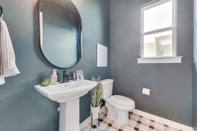 bathroom with toilet, baseboards, and a sink