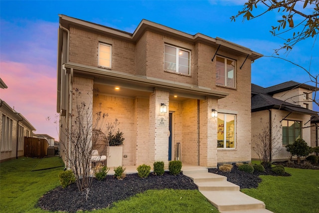 view of front of home with brick siding, a front yard, and fence