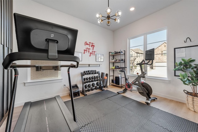 workout area with recessed lighting, an inviting chandelier, wood finished floors, and baseboards