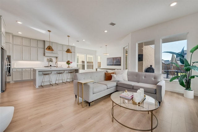 living room featuring light wood-type flooring, visible vents, baseboards, and recessed lighting