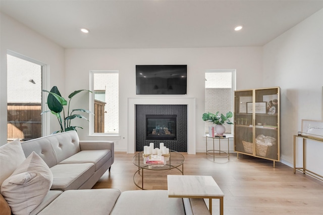 living area featuring recessed lighting, a tiled fireplace, and wood finished floors