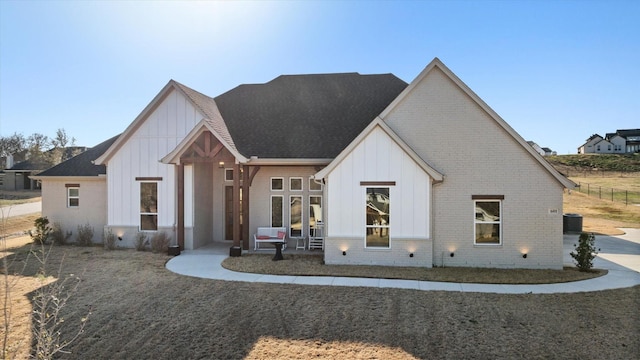 view of front of home with central AC, board and batten siding, and brick siding