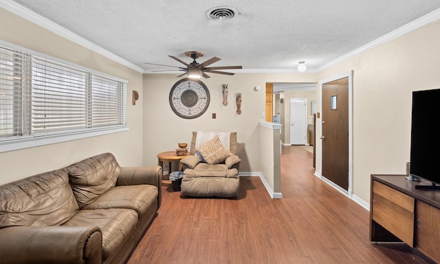 living room with visible vents, crown molding, light wood-style flooring, and a textured ceiling