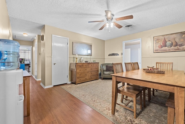 dining space featuring attic access, visible vents, a textured ceiling, and wood finished floors