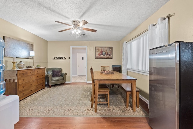 dining room with a ceiling fan, a textured ceiling, and wood finished floors