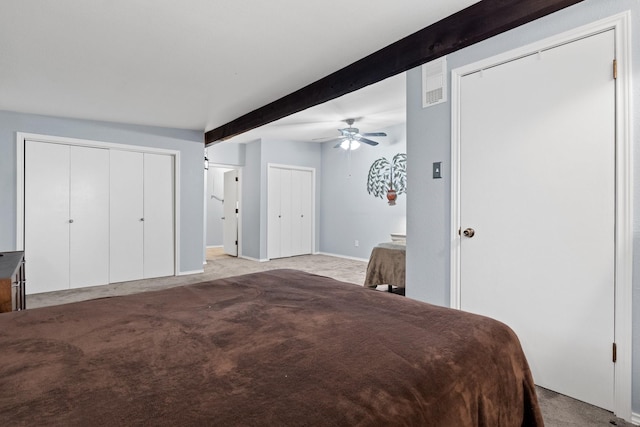 bedroom with light carpet, a ceiling fan, multiple closets, and beamed ceiling