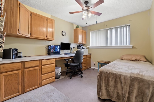 bedroom featuring light carpet, built in desk, and a textured ceiling