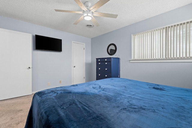 carpeted bedroom featuring a ceiling fan, visible vents, and a textured ceiling