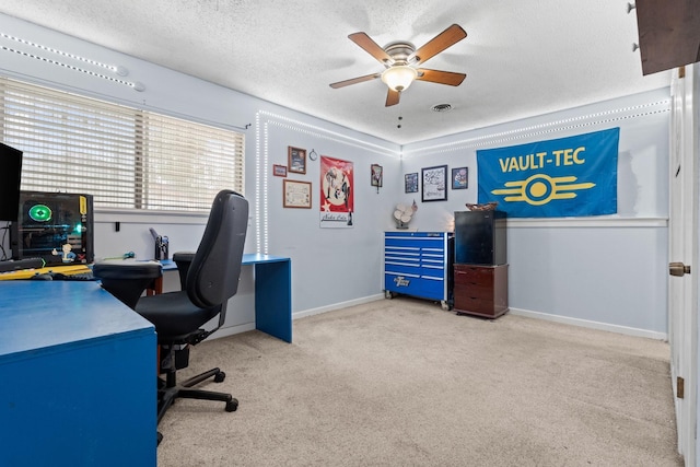 carpeted office featuring baseboards, visible vents, a ceiling fan, and a textured ceiling