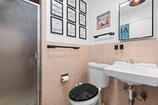 bathroom featuring a stall shower, wainscoting, tile walls, and toilet