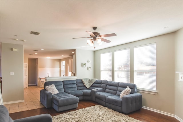 living room featuring visible vents, baseboards, wood finished floors, and a ceiling fan