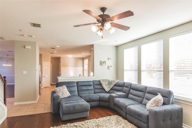 living room with light tile patterned floors, visible vents, and a ceiling fan