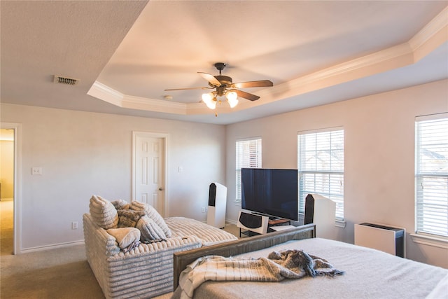 carpeted bedroom featuring visible vents, multiple windows, and a tray ceiling