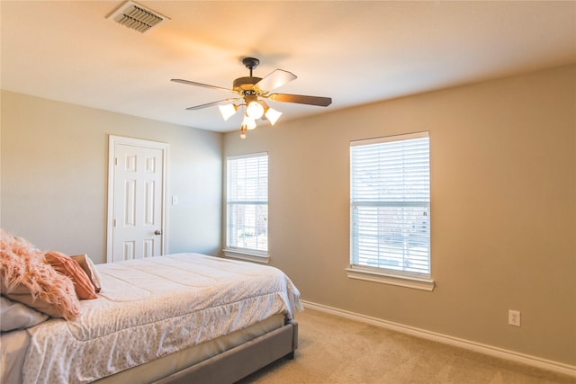 bedroom with light carpet, visible vents, a ceiling fan, and baseboards