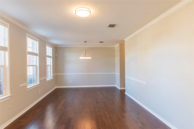 spare room with ornamental molding, dark wood finished floors, visible vents, and baseboards