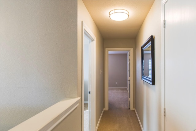 corridor featuring baseboards and light carpet